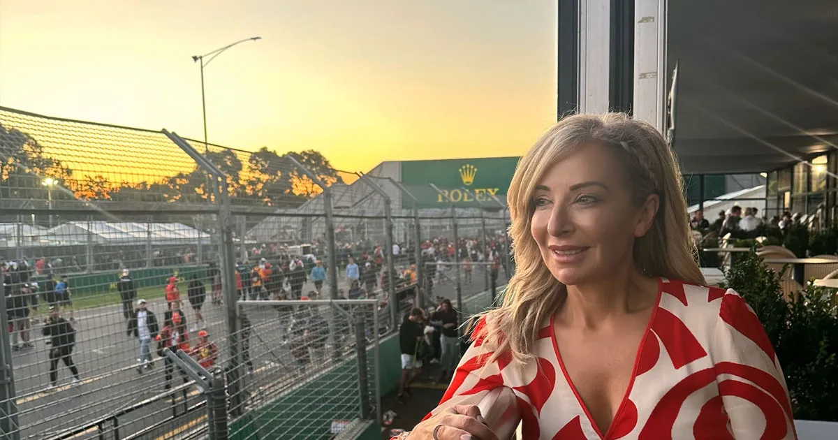A smartly dressed woman smiling at sunset at the Australian Grand Prix