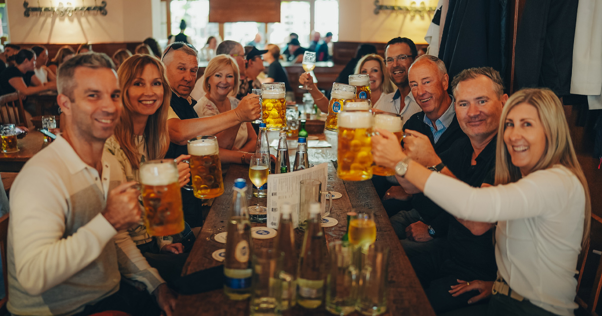 A happy group of Ultimate Driving Tours guests toasting steins at Oktoberfest