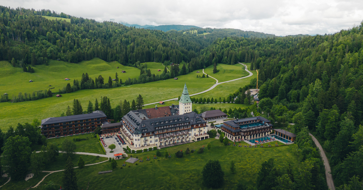 Schloss Elmau seen from an elevated view flanked by forest and valleys