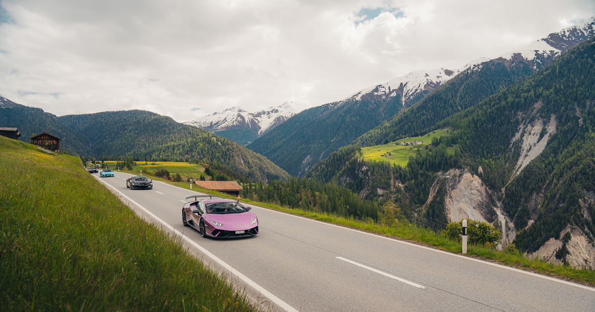 A purple Lamborghini Huracan leading a convoy of supercars through the alps on an Ultimate Driving Tours journey.