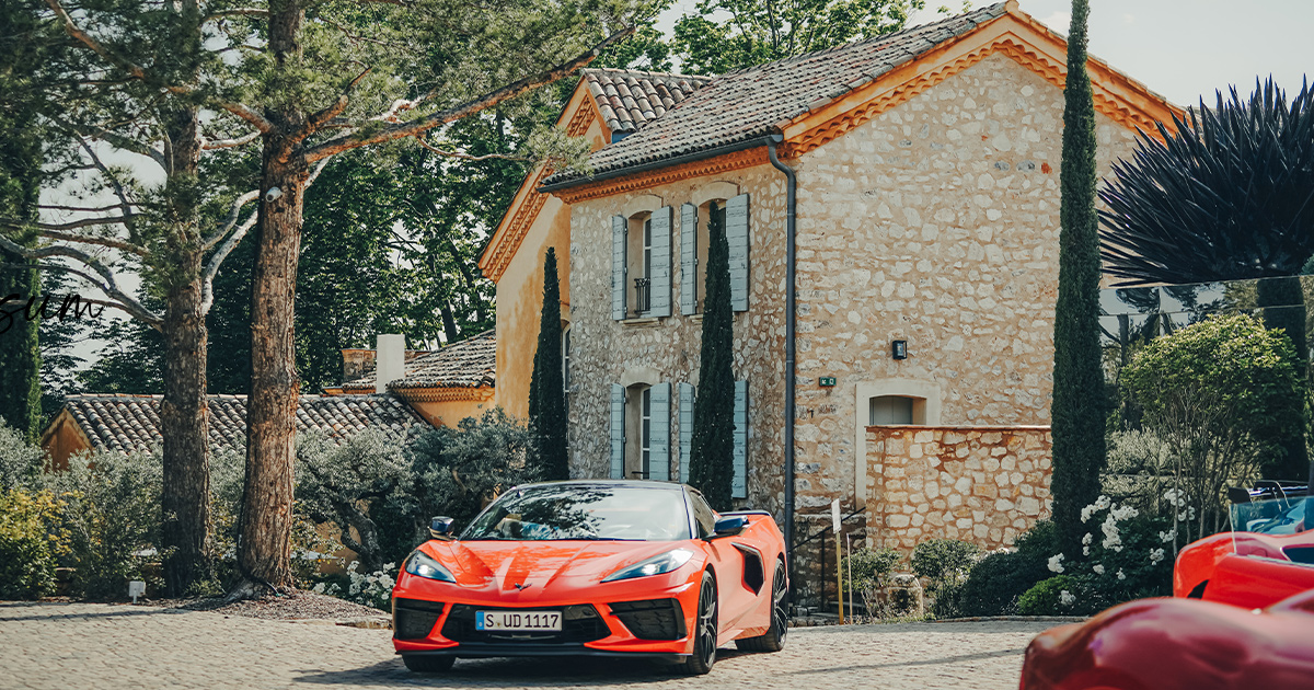 A red Chevrolet Corvette C8 in front of a historic French villa