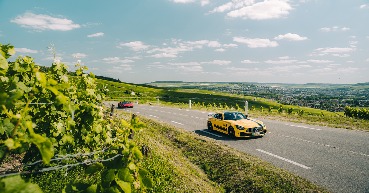 A yellow Mercedes-AMG GTR rounds a corner in the French countryside