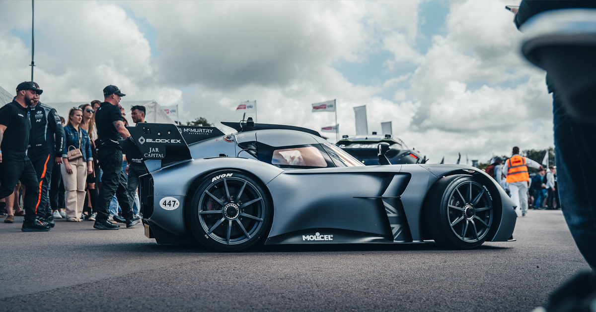 A compact race car with matte black paint and black wheels