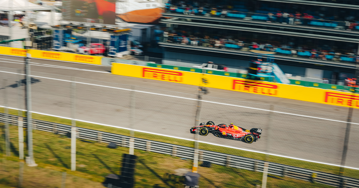 A Ferrari F1 car racing along a straight at Monza with Pirelli hoarding in the background