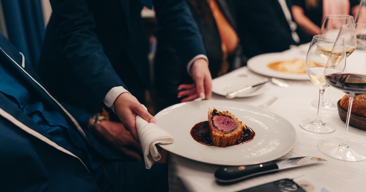 A finely plated beef Wellington with matching wine being carefully served to an Ultimate Driving Tours guests