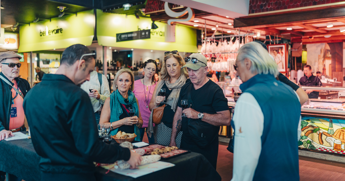 A group of Ultimate Driving Tours guests taste wine and platters at Halles de Lyon