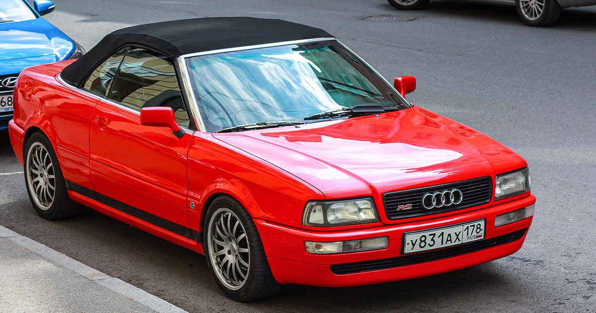 A red Audi Cabriolet with black top and red RS badging