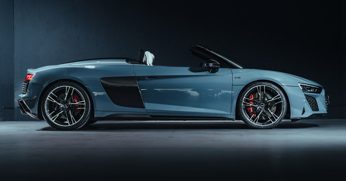 Side profile of a powder blue Audi R8 V10 Spyder with the hood down