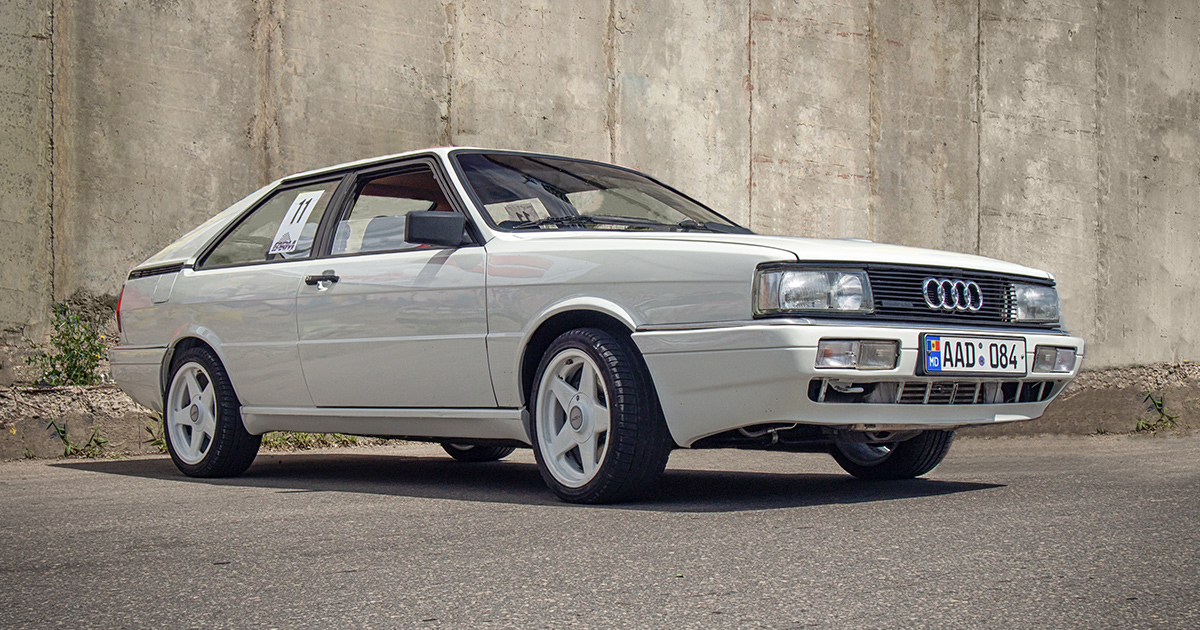 A white Audi Quattro with white five spoke wheels and the number 11 on its side window