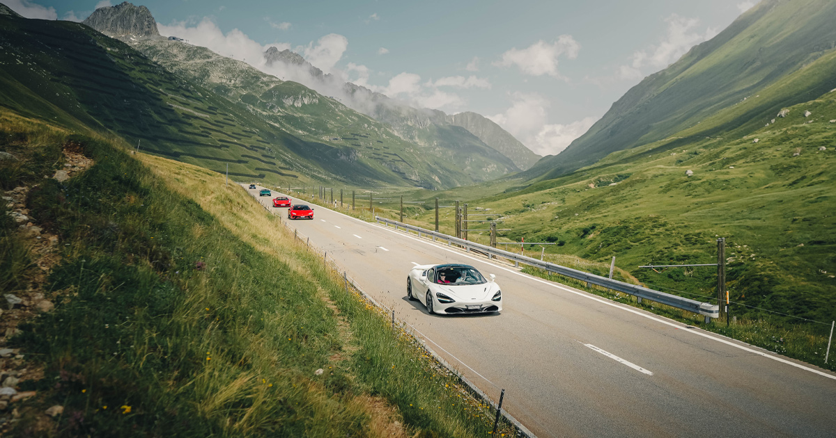 A white Mclaren 720S leads a convoy of supercars in the Swiss alps