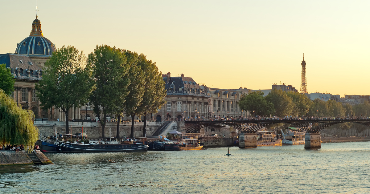 The river Seine and its banks cloaked in evening light with Eiffel Tower in the background.