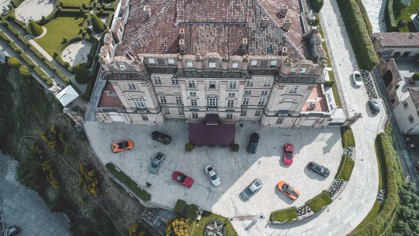 Fleet of supercars parked in front of luxury castle hotel on a European driving tour